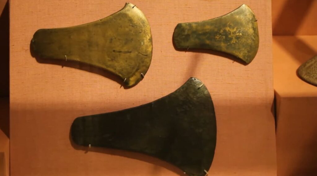 Three bronze axe heads exhibiting varying sizes and patinas